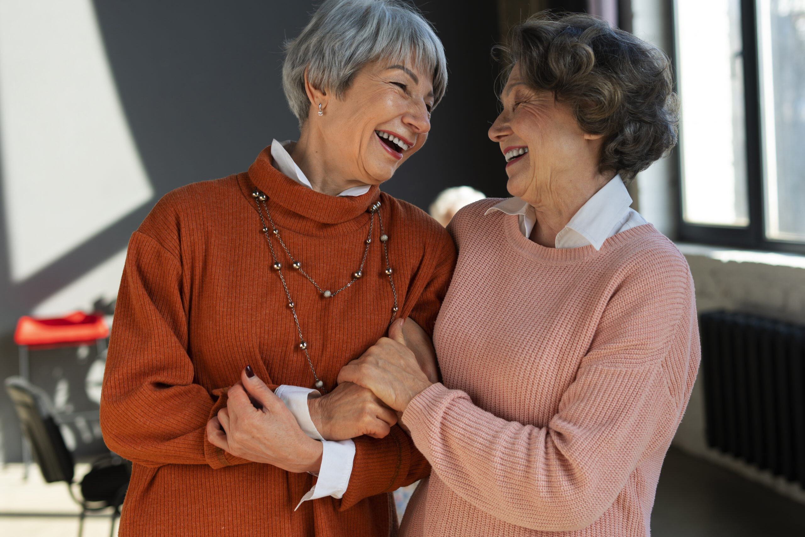 Two elder women sharing a laugh and embrace