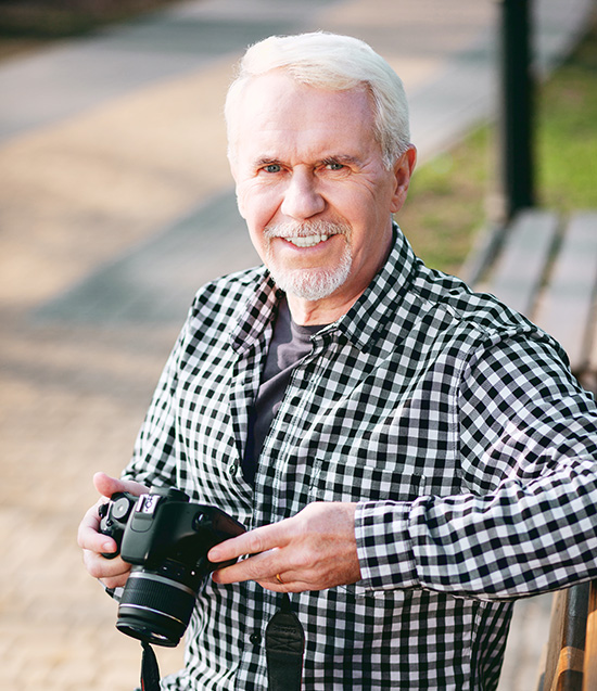 Male photographer poses on a park bench