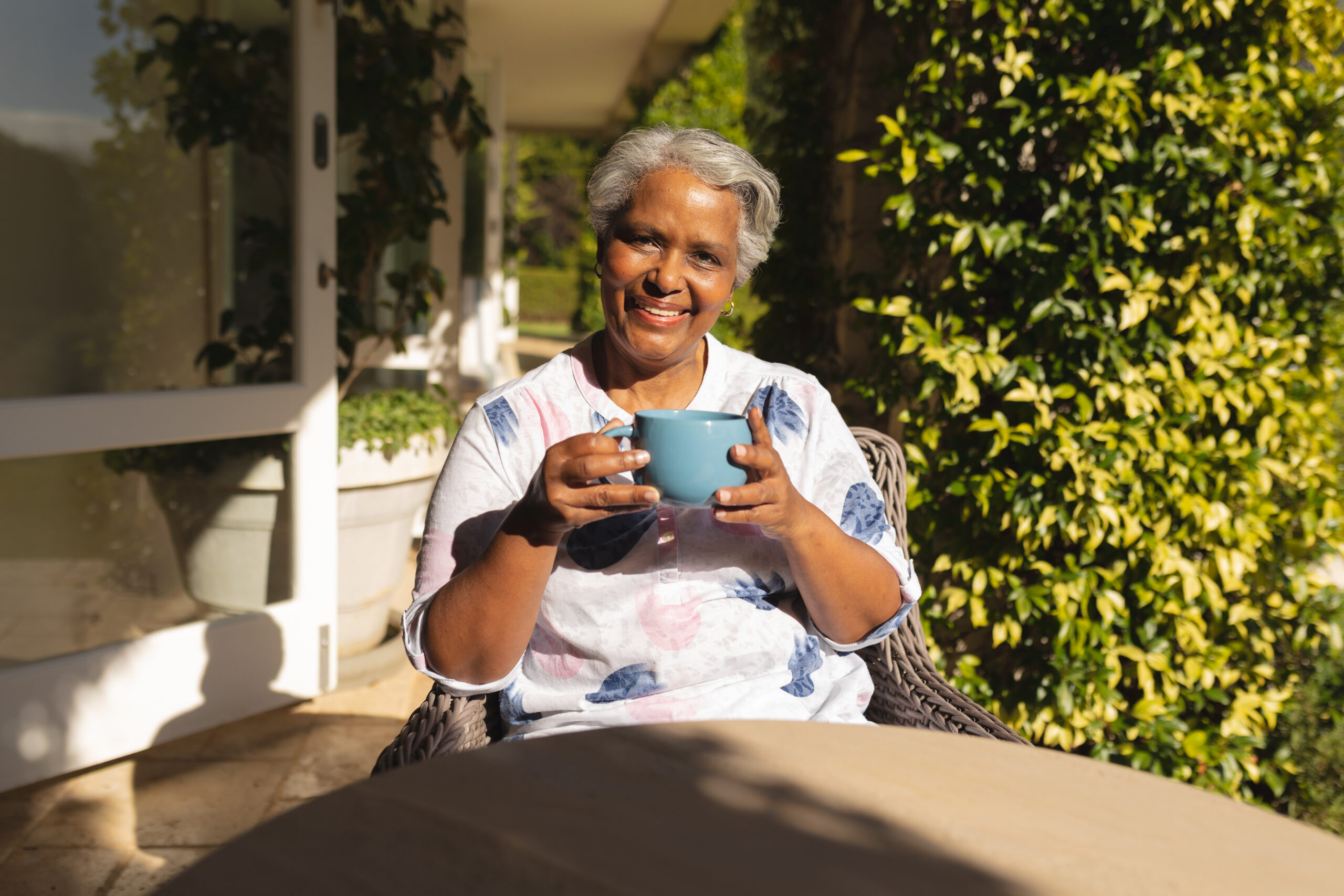 Smiling senior african american woman having tea in sunny garden. retreat, retirement and happy senior lifestyle concept.