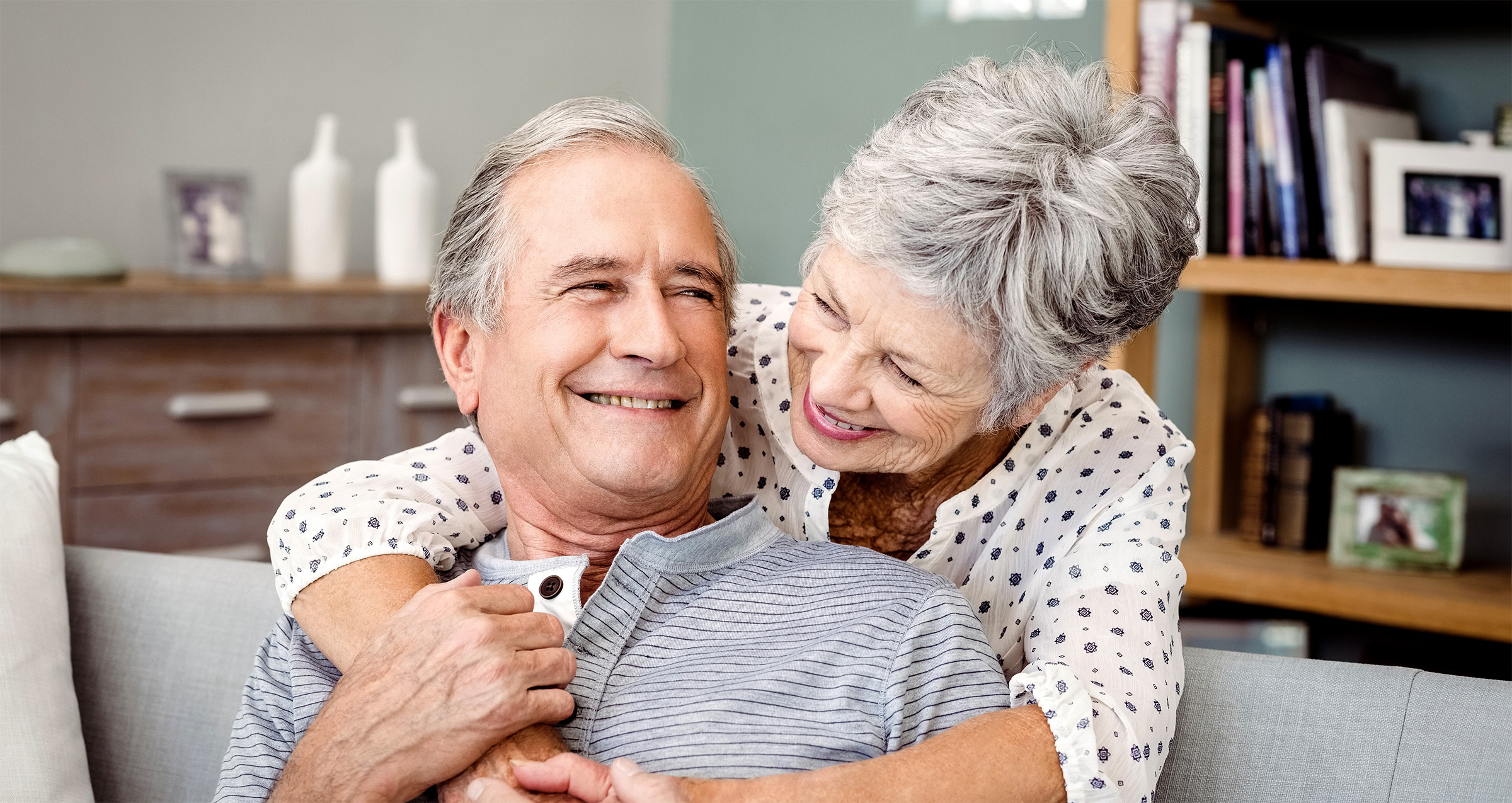 An elderly woman embracing a man sitting on a couch